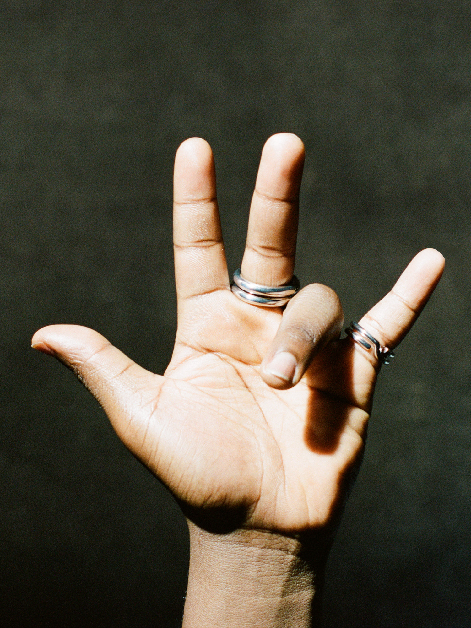 Hand with two silver keyring rings on a dark background