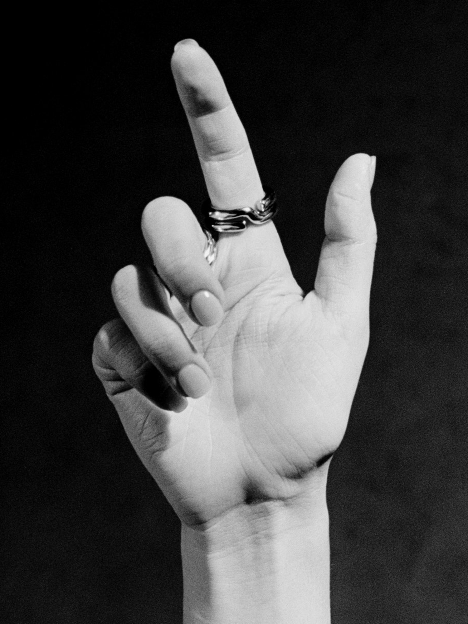 Black and white photo of a hand with two rings on a dark background
