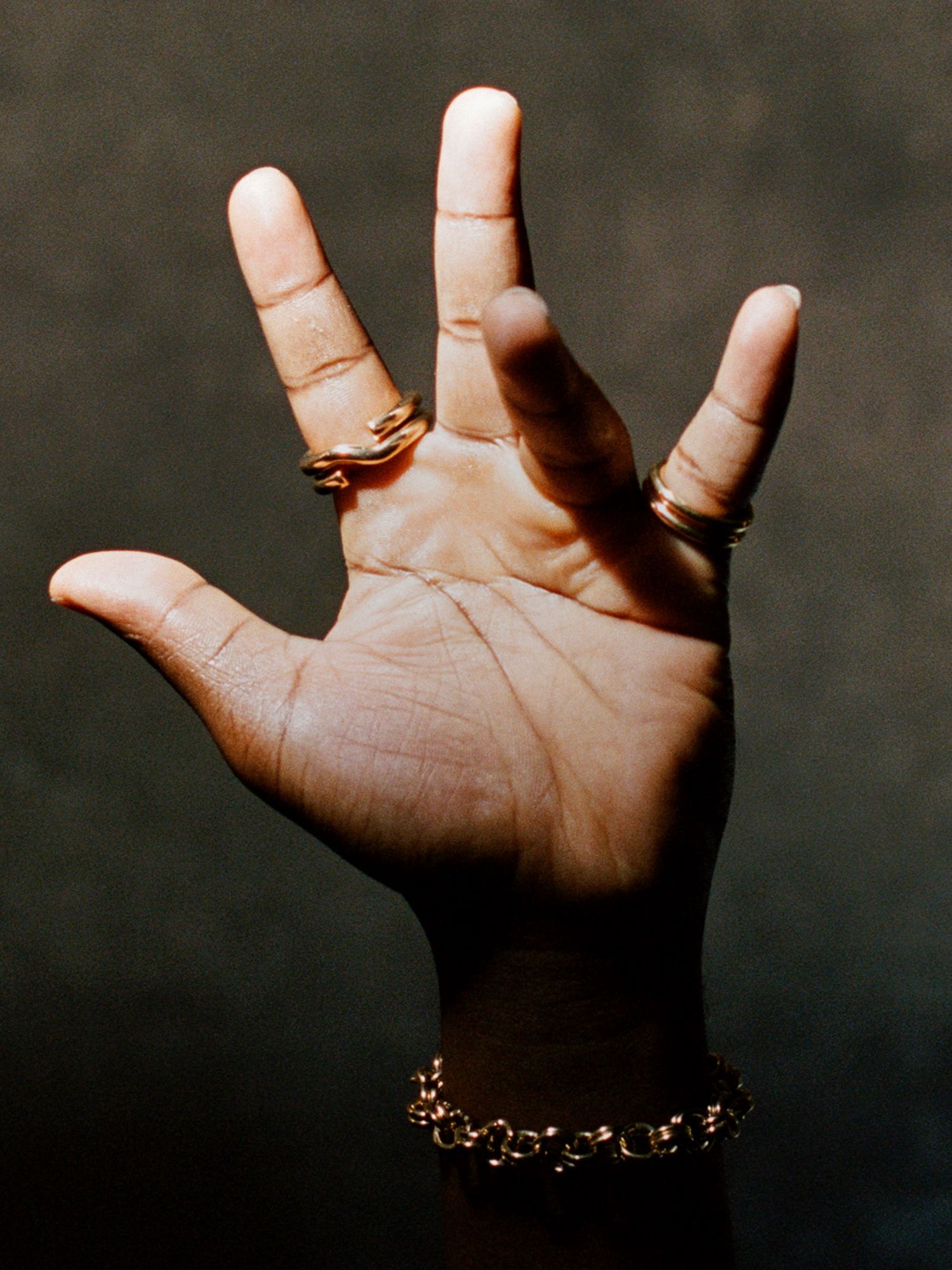 Hand with rings and a bracelet against a dark background